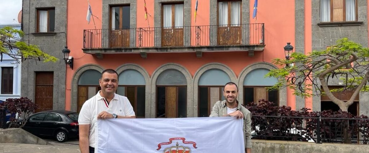 El alcalde Pedro Rodriguez junto a Manu Lujan con la bandera del municipio frente a las Casas Consistoriales