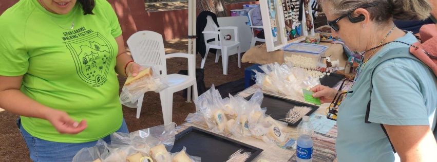 Participantes en la ruta de senderismo junto a unos de los puestos de queso de Guía instalado para la ocasión en el Área Recreativa de Santa Cristina 2