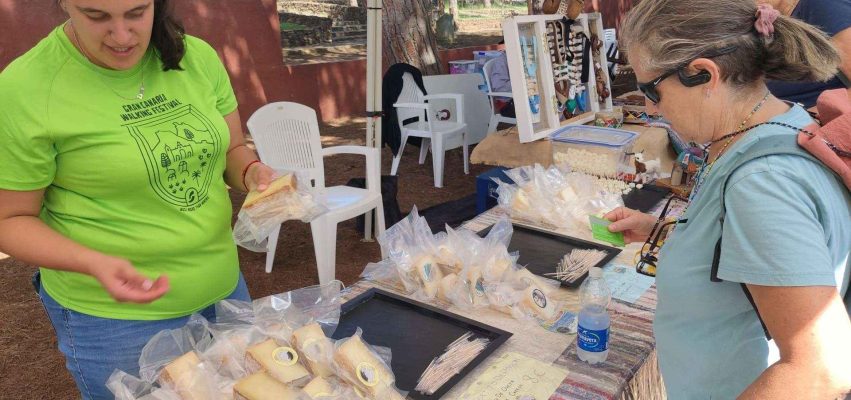 Participantes en la ruta de senderismo junto a unos de los puestos de queso de Guía instalado para la ocasión en el Área Recreativa de Santa Cristina 2