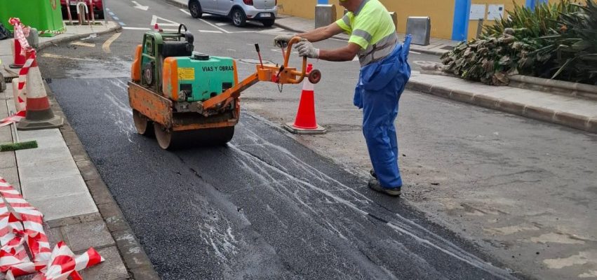 Un operario trabaja en la reparación del asfalta dañado por la quema de contenedores en la calle Drago